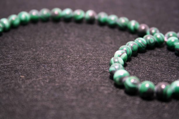 istock Green beads on a black felt background. 1292397887