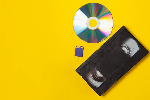 video cassette videotape, compact disc, flash sd card on a yellow background. flat lay concept. - dvd obsolete cd cd rom imagens e fotografias de stock