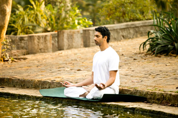 istock Man meditating by lake at park 1292399289