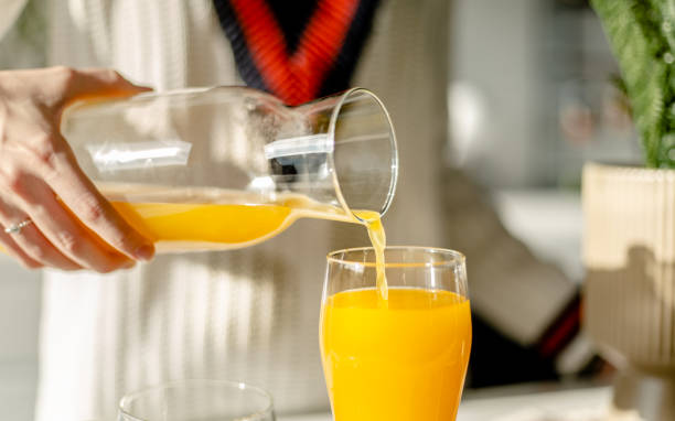beber jugo en la cocina de cerca - zumo de naranja fotografías e imágenes de stock