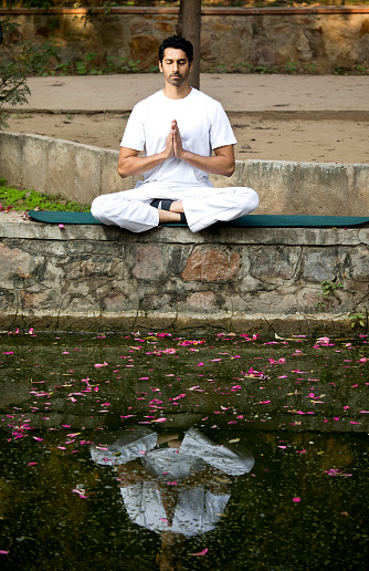 Man meditating in lotus position at lakeshore