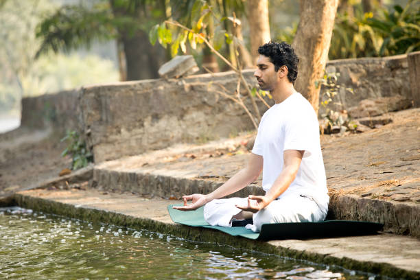 istock Man meditating by lake at park 1292400111