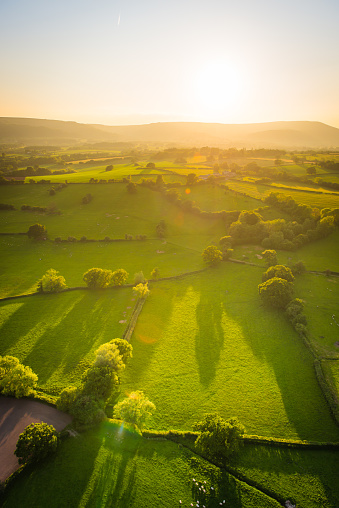 Warm light of sunset illuminating the picturesque patchwork quilt landscape of green pasture, agricultural crops, farms, villages and the distant mountains of South Wales, UK.