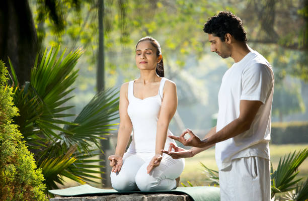 istock Instructor teaching yoga pose to woman at park 1292400849