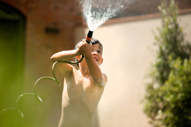 istock Child playing with a hose at the garden. 1292401516