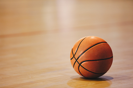 Orange basketball ball on wooden parquet. Close-up image of basketball ball over floor in the gym