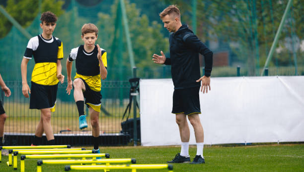 ladder drills for soccer. group of young boys on football training with coach. young man as a sports trainer showing to male youth soccer team how to exercise on agility ladder - youth league imagens e fotografias de stock