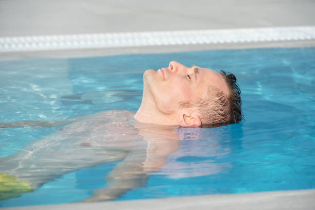 istock Head of young relaxed man keeping his eyes closed while enjoying warm water 1292402308