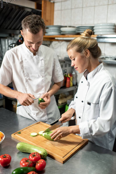 istock Chef with knife peeling avocado while his female trainee cutting fresh zucchini 1292402410