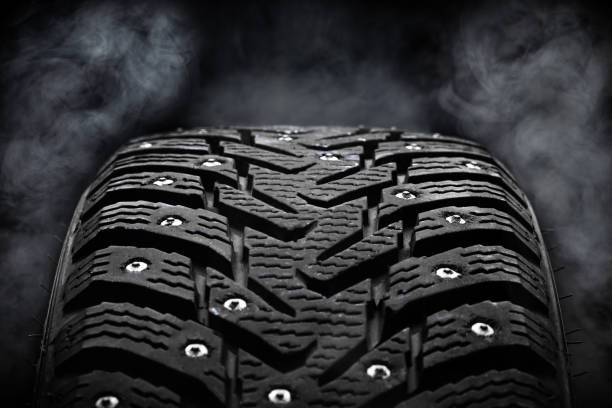 winter studded tyre dark moody. steam on background. studio shot. tyres industry concept. copy space stock photo