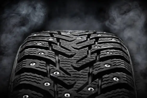 winter studded tyre dark moody. steam on background. studio shot. tyres industry concept. copy space.