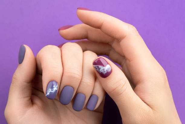 istock Beautiful purple burgundy matte manicure on creative background. 1292404361
