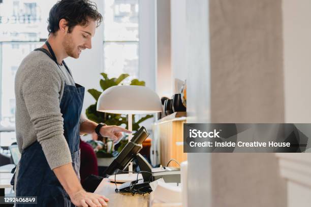 Side View Portrait Of Young Goodlooking Caucasian Barista Working On The Cash Point In Cafeteria Stock Photo - Download Image Now