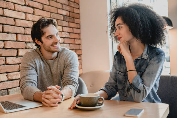 istock Happy young mixed-race couple talking using laptop in small cafe 1292406978