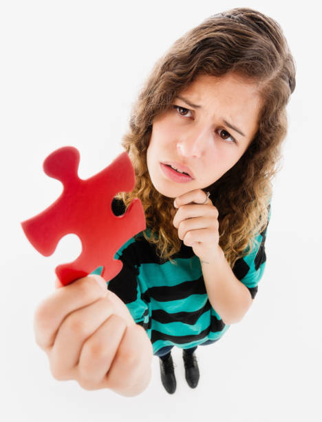 istock Beautiful young woman looks puzzled by a large jigsaw piece as she strives for a solution 1292407140