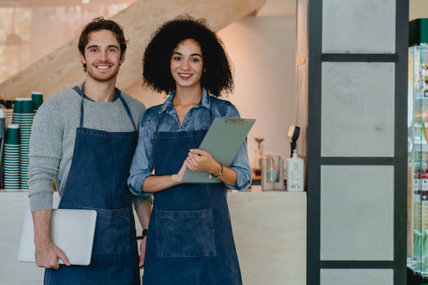 istock Confident young mixed-race cafe workers holding notepods in coffee shop 1292407248