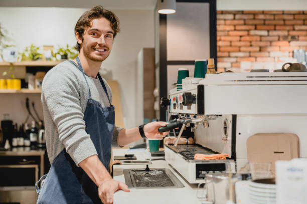 istock Confident 20s handsome barista making coffee using coffee machine in cafeteria 1292407743