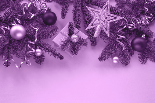 Fir branches, gift in a box and baubles festive background. Christmas concept. Top view, flat lay, copy space. Toned in purple