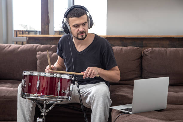 istock A young man with headphones learns to play the drum using online lessons. 1292408839