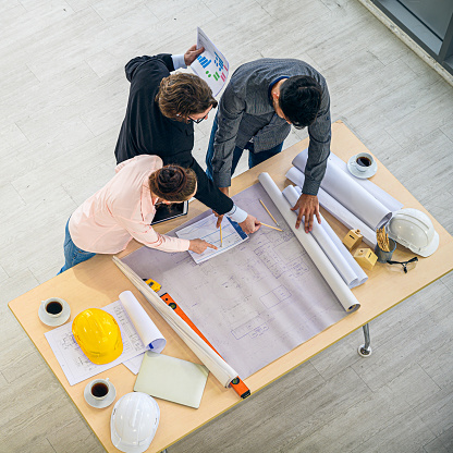 Top view of Caucasian engineer group teamwork meeting for planning project on the table with paperwork. Corporation creativity people.