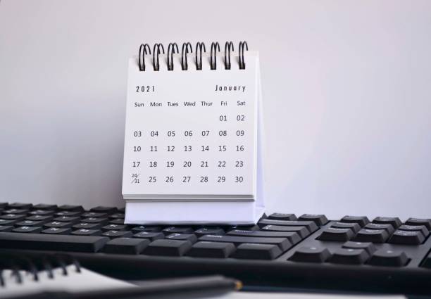 istock White January 2021 calendar on a blurred keyboard, pen and notebook with white backgrounds. New Year Concept 1292414465