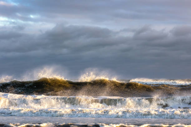 istock Rough surf under dark ominous storm clouds, with spray coming off large waves breaking. 1292415464
