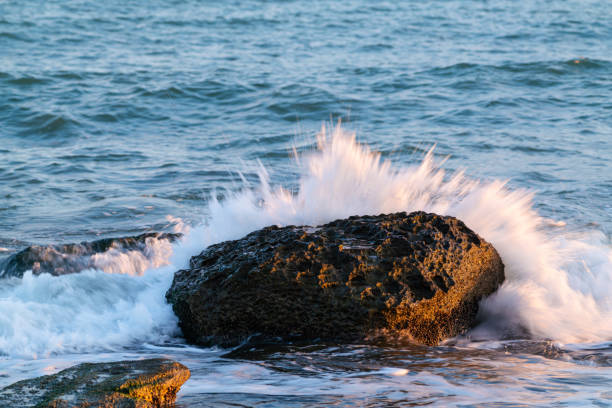 Big stone and crashing waves on sea shoreRocky coastline and  crashing waves