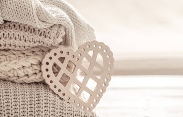 istock Decorative wooden heart on a stack of knitted items close up. 1292418614