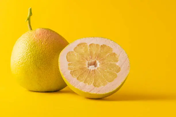 horizontal view in foreground of a grapefruit and half grapefruit isolated on yellow background