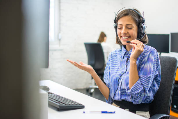 istock Friendly beautiful customer service agent woman chatting with client using hands-free headset at office. 1292423482