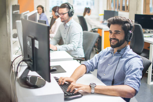 istock Handsome young business man with headset working in call center. 1292423538