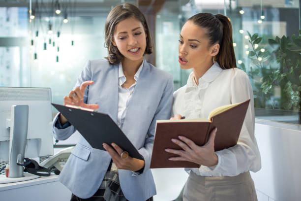 istock Two attractive business women working together in office. 1292423719
