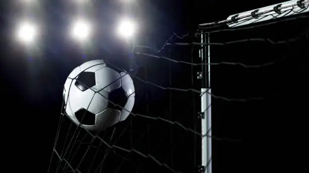 Soccer ball flying into net, goal success concept. Isolated on black background
