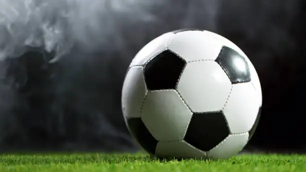 Soccer ball on lawn with smoke. Isolated on black background