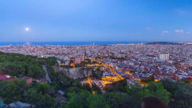 View of Barcelona day to night , the Mediterranean sea, The tower Agbar and The twin towers from Bunkers Carmel. Catalonia, Spain View of Barcelona skyline day to night transition , the Mediterranean sea, The tower Agbar and The twin towers from Bunkers Carmel. Catalonia, Spain. View from Bunkers Carmel parallel port stock pictures, royalty-free photos & images