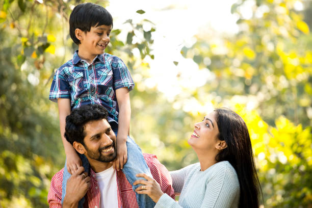 istock Mother with father carrying son on shoulder at park 1292434770