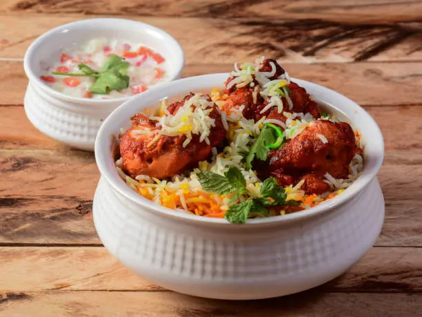 Chicken Tikka Biryani made of Basmati rice cooked with masala spices, served with yogurt, selective focus