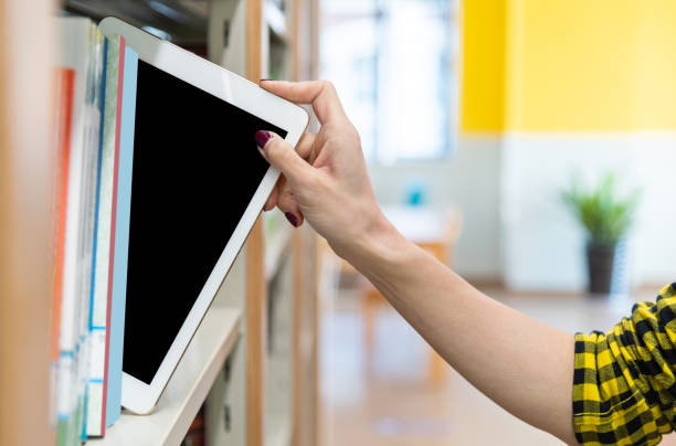 femme choisissant la tablette numérique de l’étagère - digital tablet student studying learning photos et images de collection