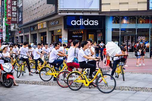 Changsha City, Hunan Province, China, June, 2017. A group of young people with yellow shared bikes at Changsha city's popular commercial street Huangxinglu.