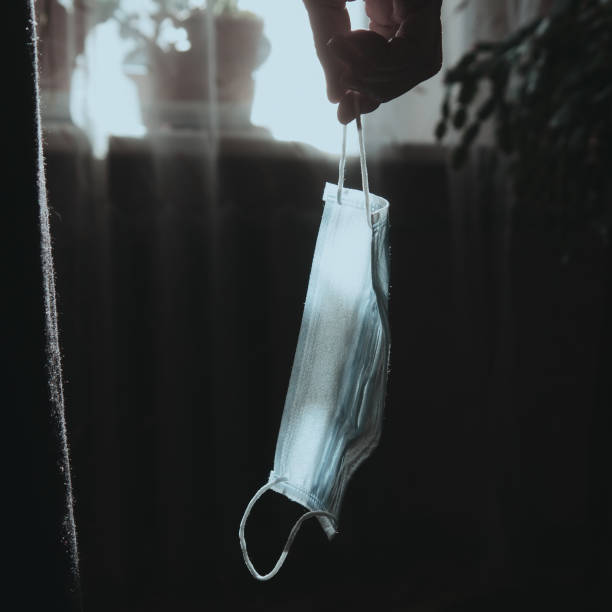 istock Old woman holding face mask in hand 1292440336