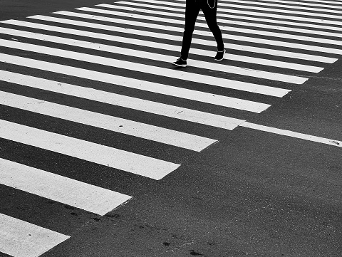 One people crossing the street on zebracross eith black and white style photo. Walk alone and safety procedure on the road