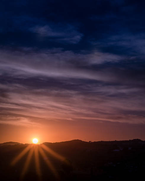 Beautiful sunset with a starry sun and a yellow and blue sky full of clouds in the golden hour in Benitachell, Alicante, Spain
