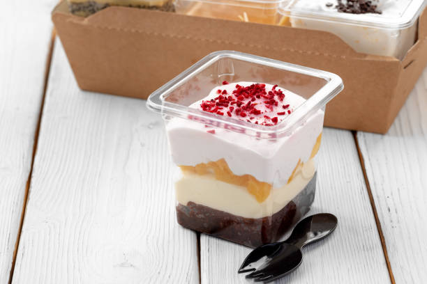 Creamy dessert in a plastic box on wooden table Creamy dessert in a plastic box on wooden table close up cake jar stock pictures, royalty-free photos & images