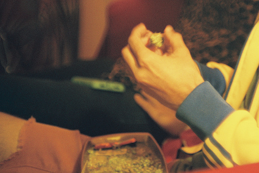 A 35mm film photograph of a person rolling a joint filled with cannabis