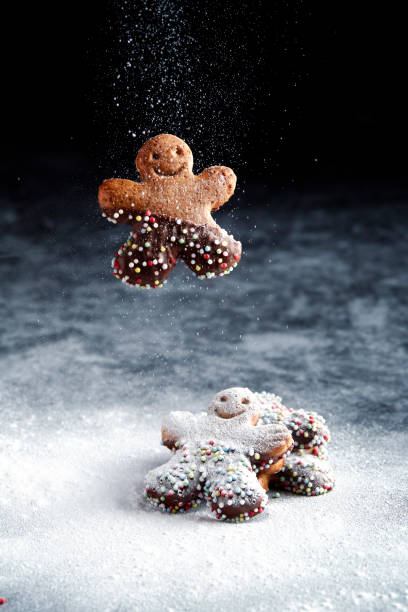 istock A chocolate gingerbread man cookie falls onto another stack of cookies. Glaced Sugar snowing 1292447587