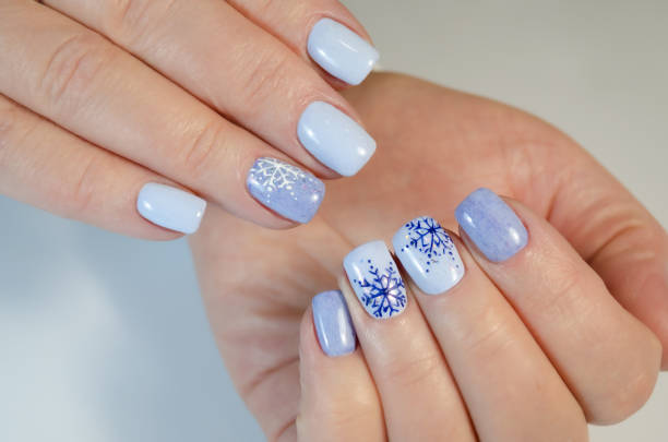 The hand of a young woman with a blue manicure and design for the New year and Christmas. The hand of a young woman with a blue manicure and design for the New year and Christmas. christmas nails stock pictures, royalty-free photos & images