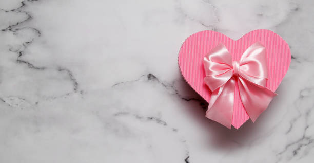 istock Pink Gift box heart shape on marble bacground with copy space banner format 1292453084