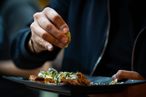 Men squeezing lime into the taco del pastor indoors, close up