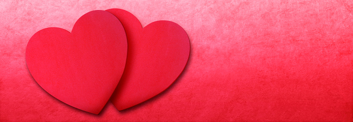 Two overlapping red hearts on a red background with ample room for copy and text.