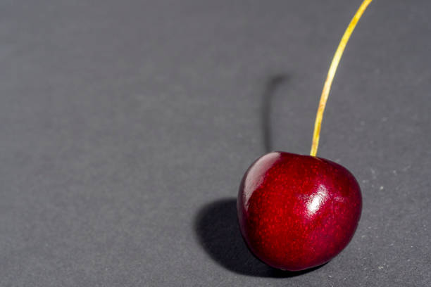 istock bright juicy ripe cherry berry isolated on a dark background. Copy space 1292457010